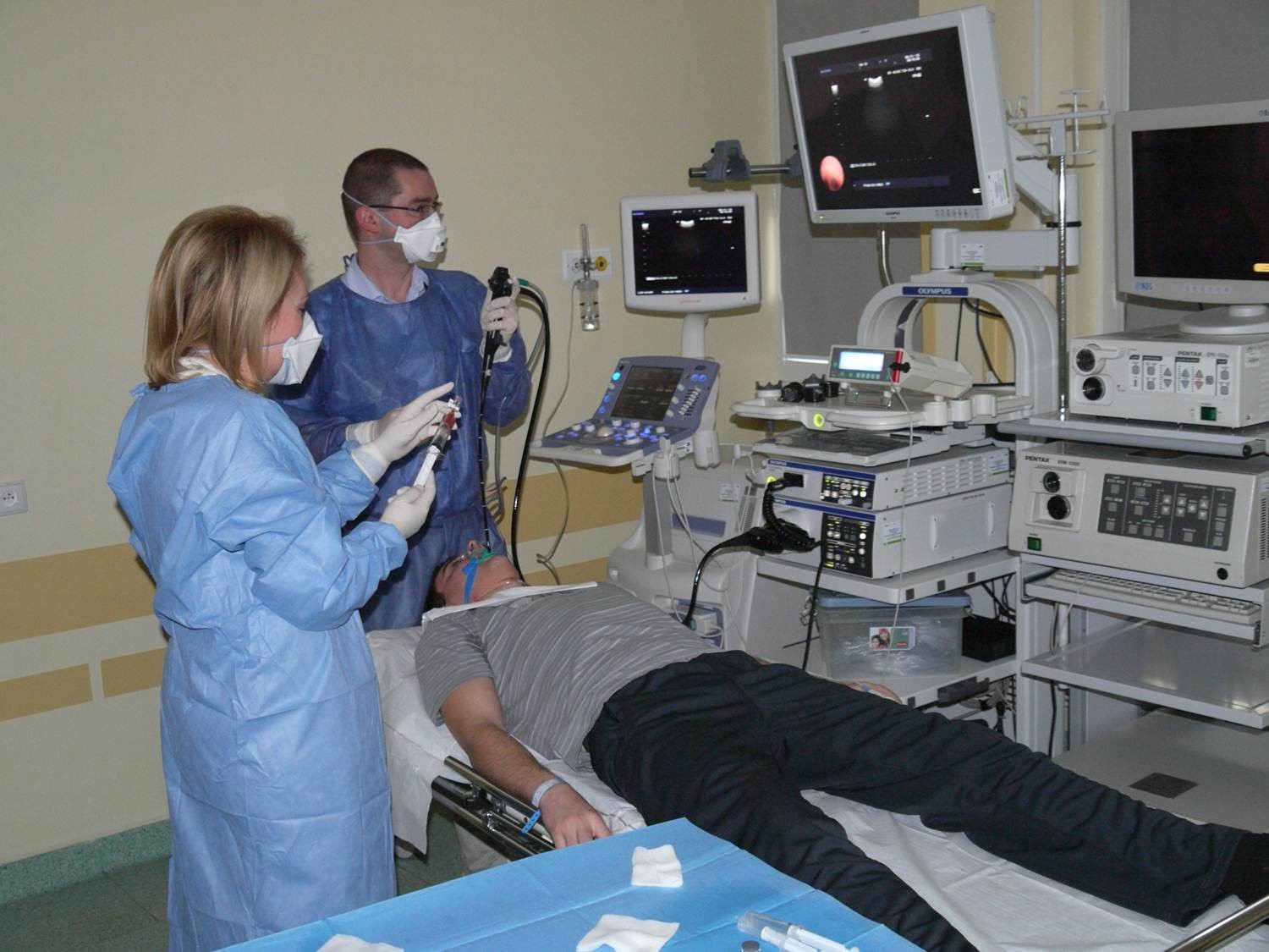 Lekarze w maskach i stroju medycznym w gabinecie z nowym sprzętem. Pacjent leżący na stole